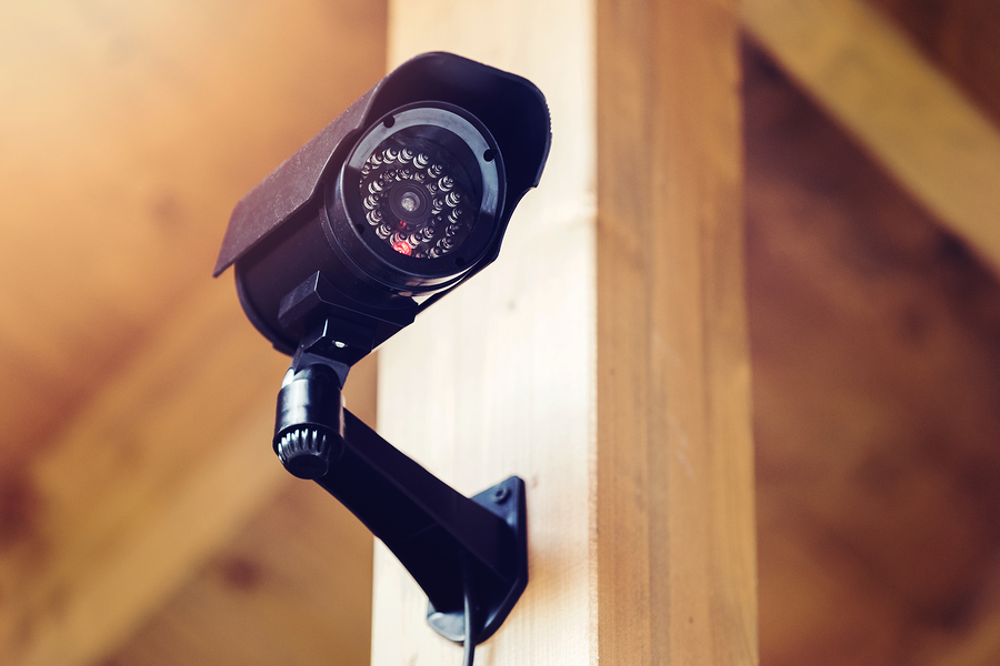 black security surveillance camera mounted on the wooden pole